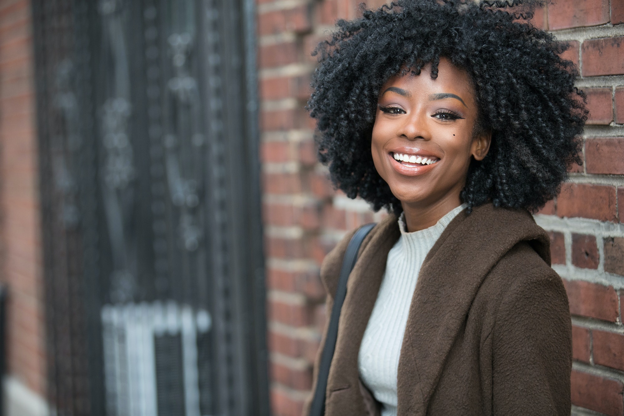Happy African American woman near brick wall outside